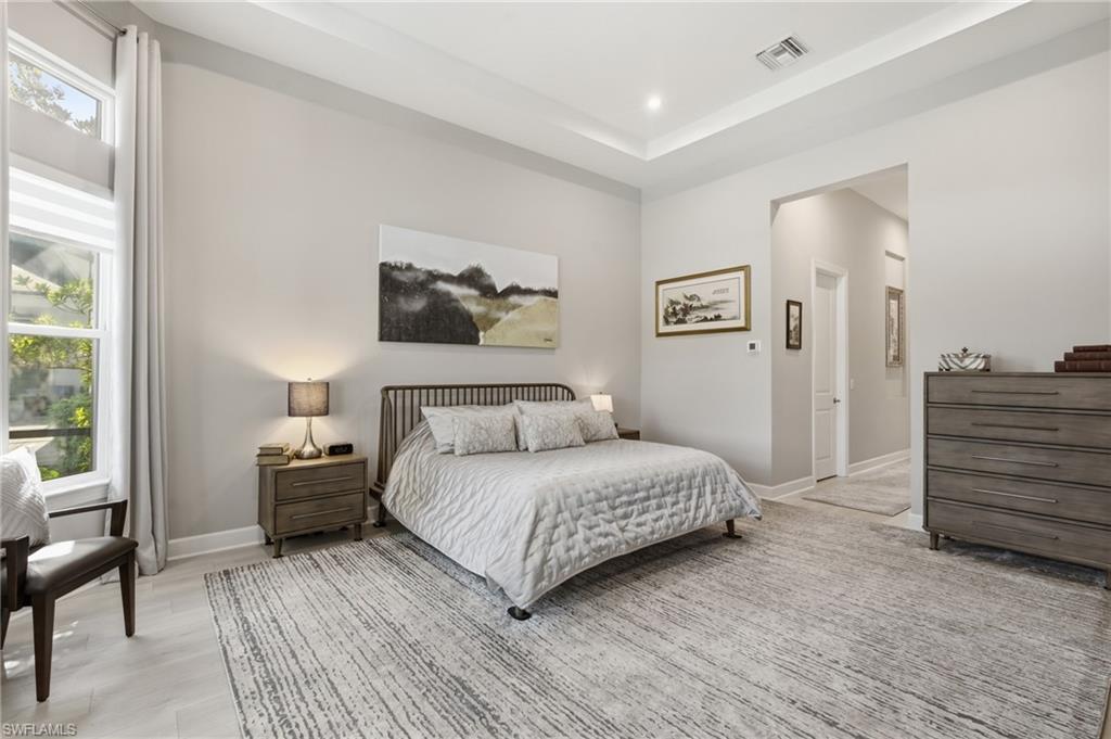 Spacious room featuring light-toned walls, a tray ceiling with recessed lighting, and large windows with privacy blinds