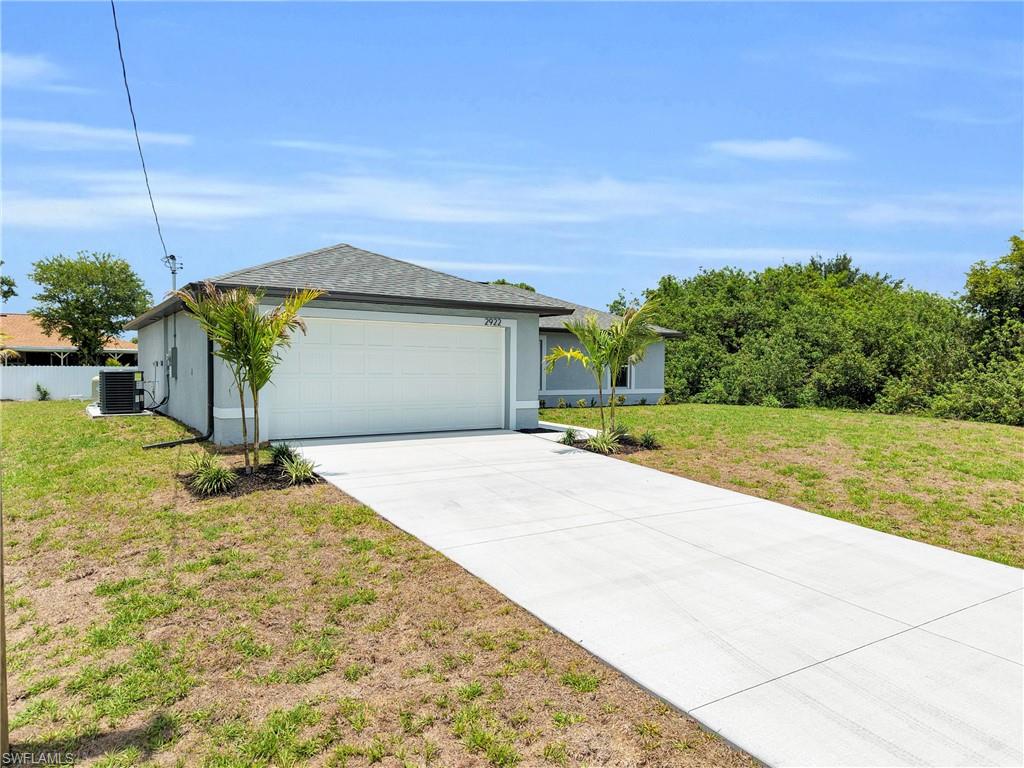 Contemporary single-story residence featuring a front-facing garage, concrete driveway, and mature landscaping