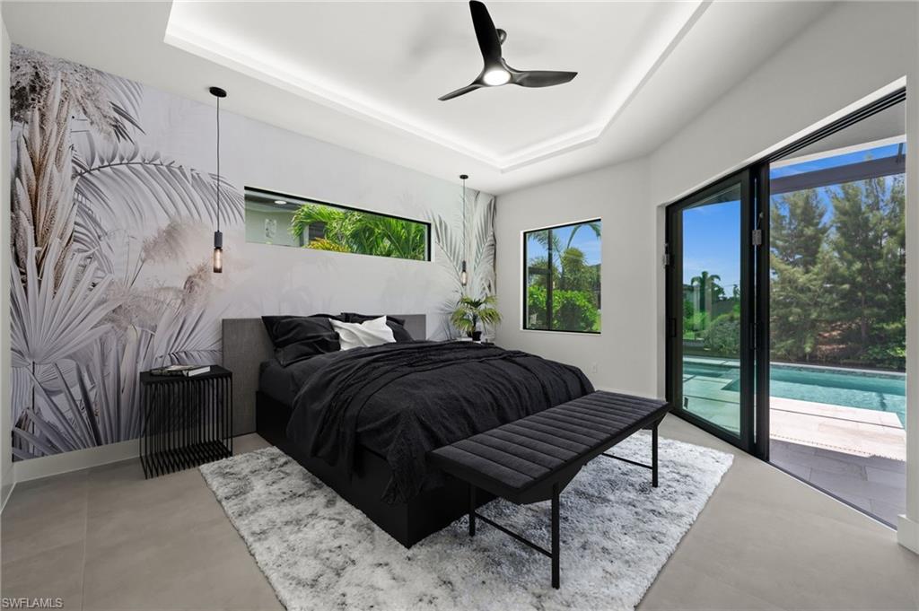 Spacious room with tray ceiling, modern ceiling fan, and large format tile flooring