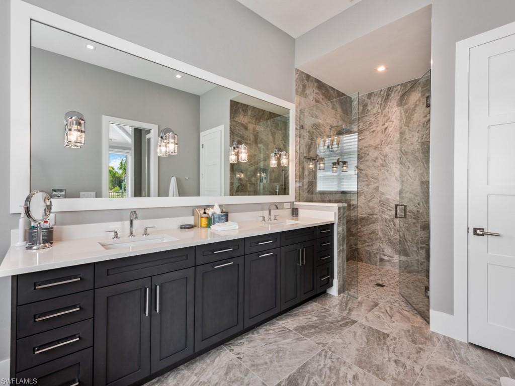 Bathroom with tile patterned flooring, dual vanity, and an enclosed shower