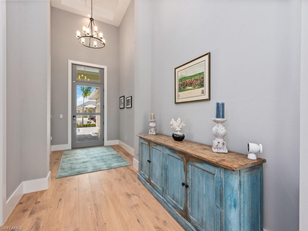 Entrance foyer featuring an inviting chandelier, light hardwood / wood-style flooring, and a towering ceiling