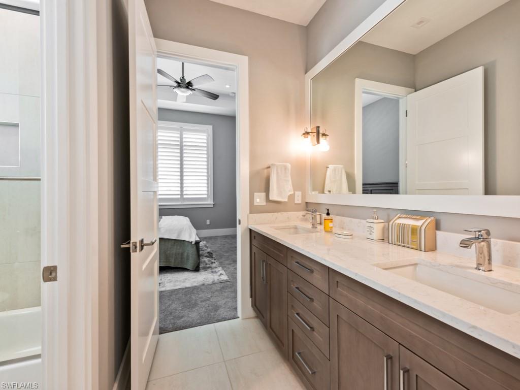 Bathroom with ceiling fan, tile patterned floors, and double sink vanity