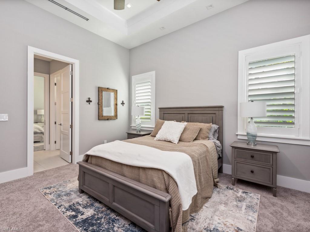Bedroom with light carpet, multiple windows, and ceiling fan