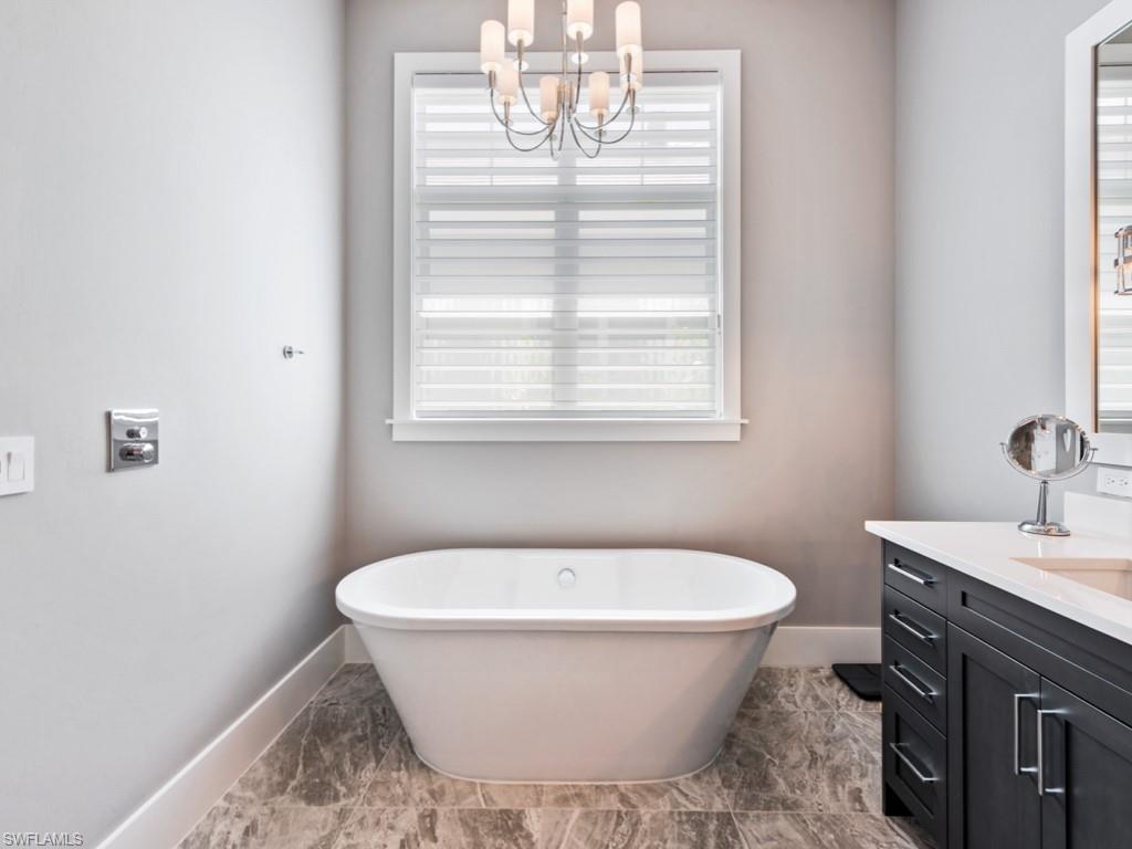 Bathroom with vanity, a chandelier, tile patterned flooring, and a bathtub