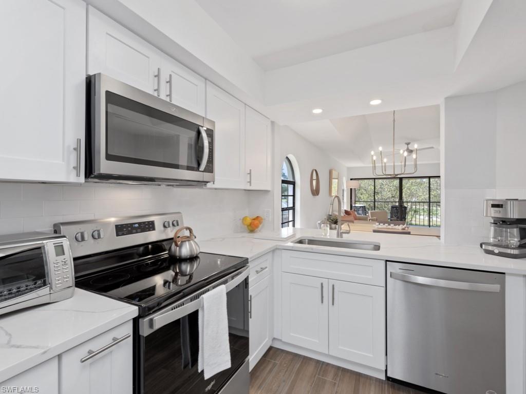 Kitchen featuring stainless steel appliances, white cabinets, tasteful backsplash, and sink