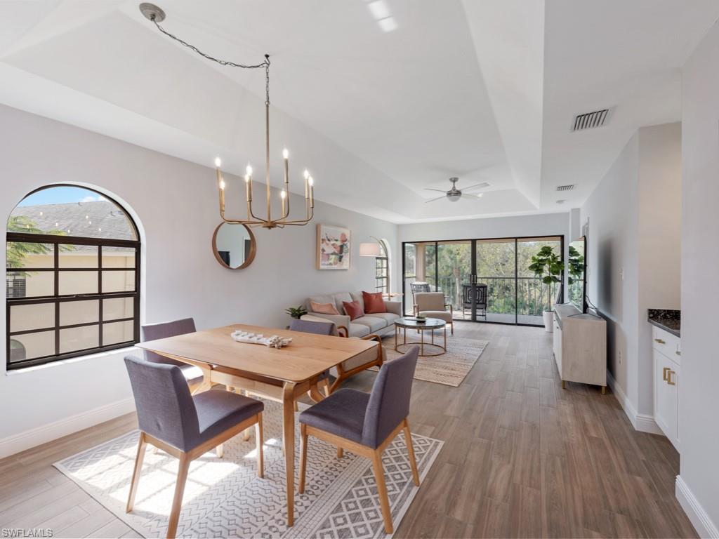 Dining room featuring hardwood / wood-style floors, a raised ceiling, and ceiling fan with notable chandelier