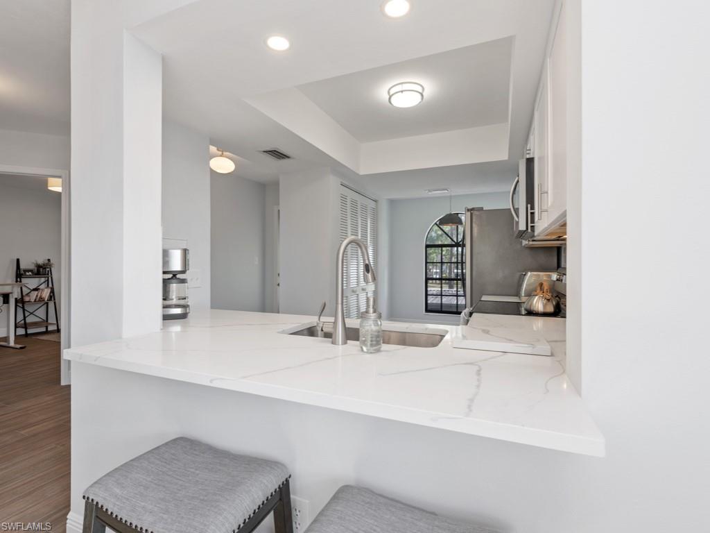 Kitchen with light stone counters, sink, hardwood / wood-style flooring, and kitchen peninsula