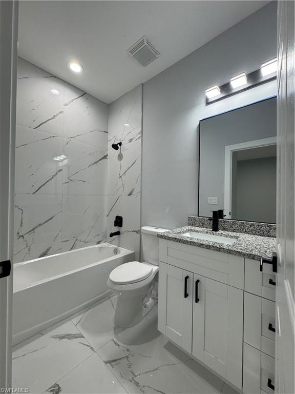 Full bathroom with toilet, vanity, and tiled shower / bath