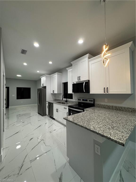 Kitchen with fridge, white cabinetry, stove, and kitchen peninsula