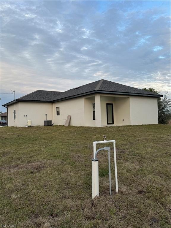 Rear view of property with cooling unit and a yard
