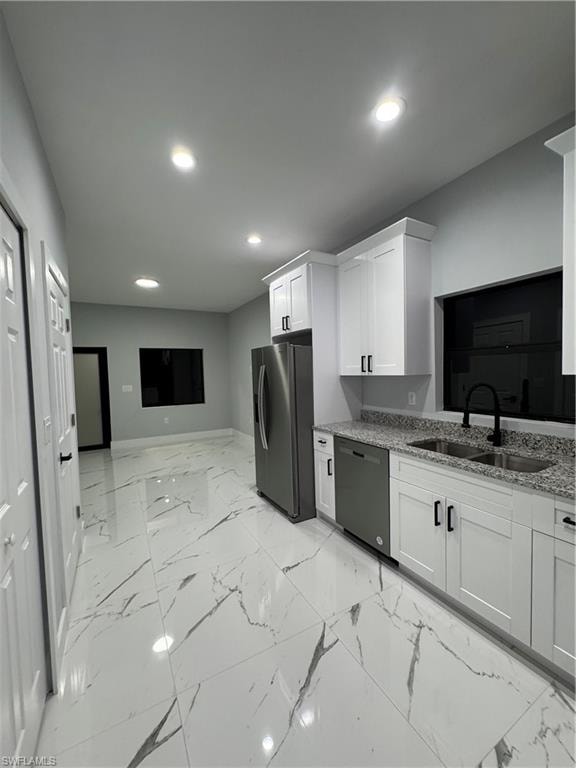 Kitchen with stainless steel refrigerator, light stone countertops, dishwashing machine, white cabinets, and sink