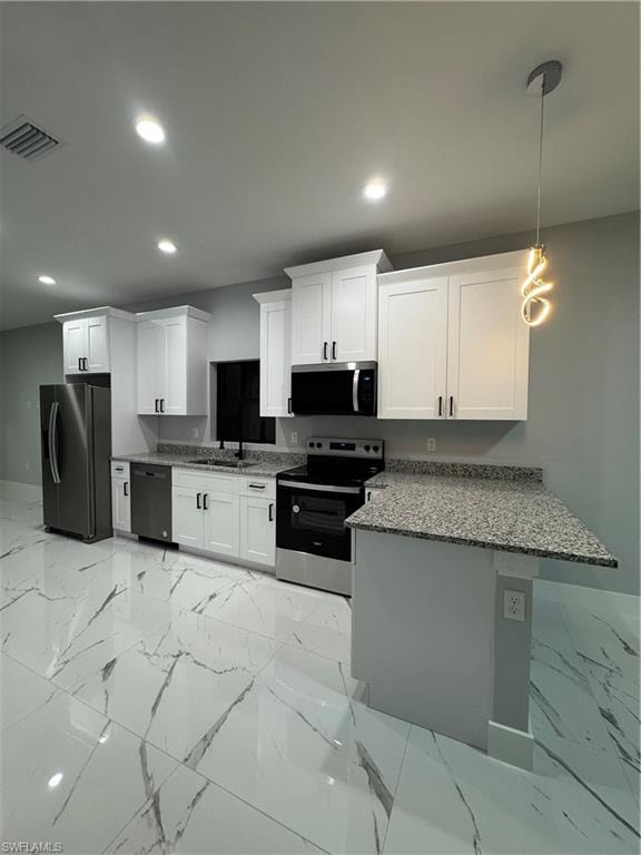 Kitchen featuring dishwasher, hanging light fixtures, refrigerator, white cabinetry, and stove