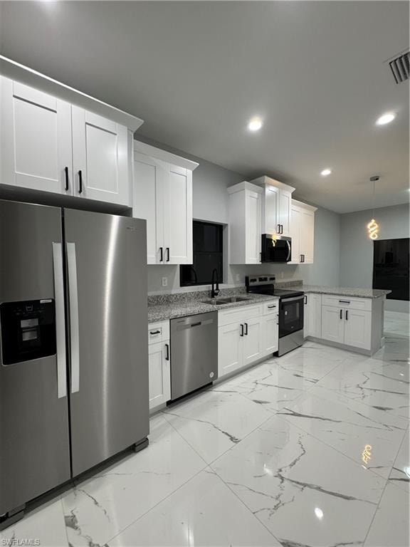 Kitchen featuring white cabinetry, dishwasher, refrigerator, stove, and hanging light fixtures