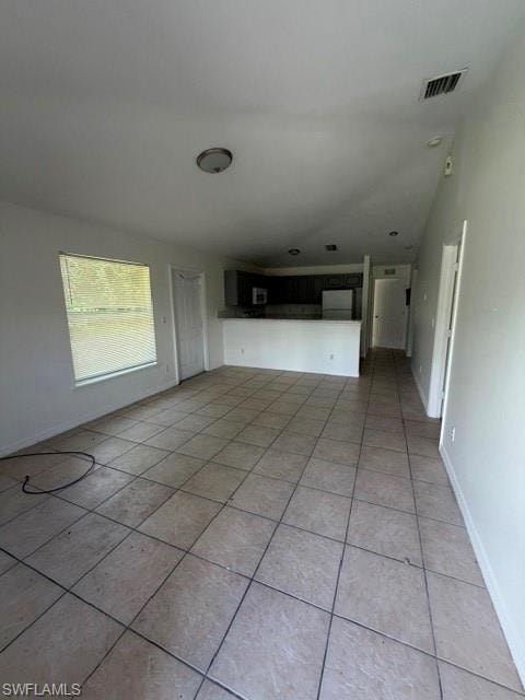 Spacious open-concept room featuring light-toned tile flooring, neutral wall finishes, and a large window with horizontal blinds