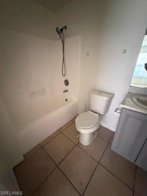Bathroom featuring a white tub and shower combination with a handheld showerhead, a white toilet, and a vanity with a light-colored countertop and grey cabinetry