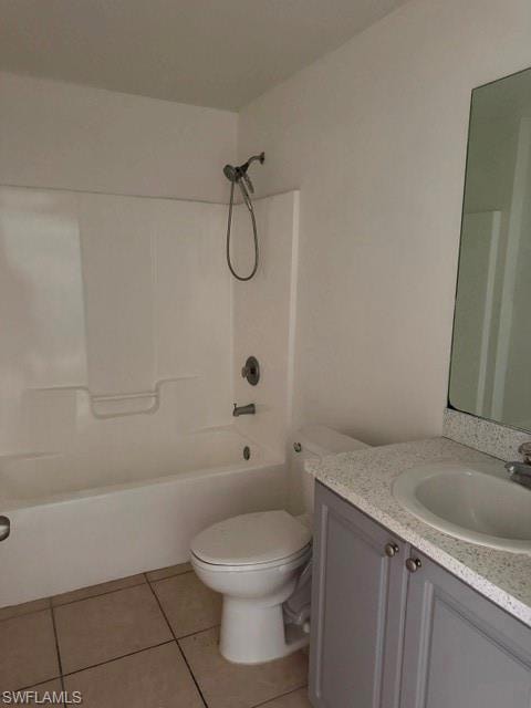 Bathroom featuring a white tub and shower combination with chrome fixtures, a toilet, a vanity with gray cabinetry, a speckled countertop, and an integrated sink