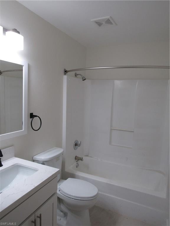 Bathroom featuring a white vanity with a light-colored countertop, an undermount sink, a toilet, and a shower-tub combination with a curved shower rod