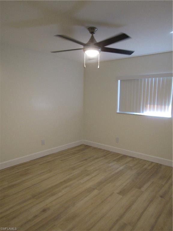 Interior space featuring wood-finish flooring, a ceiling fan with integrated lighting, and a window with horizontal blinds