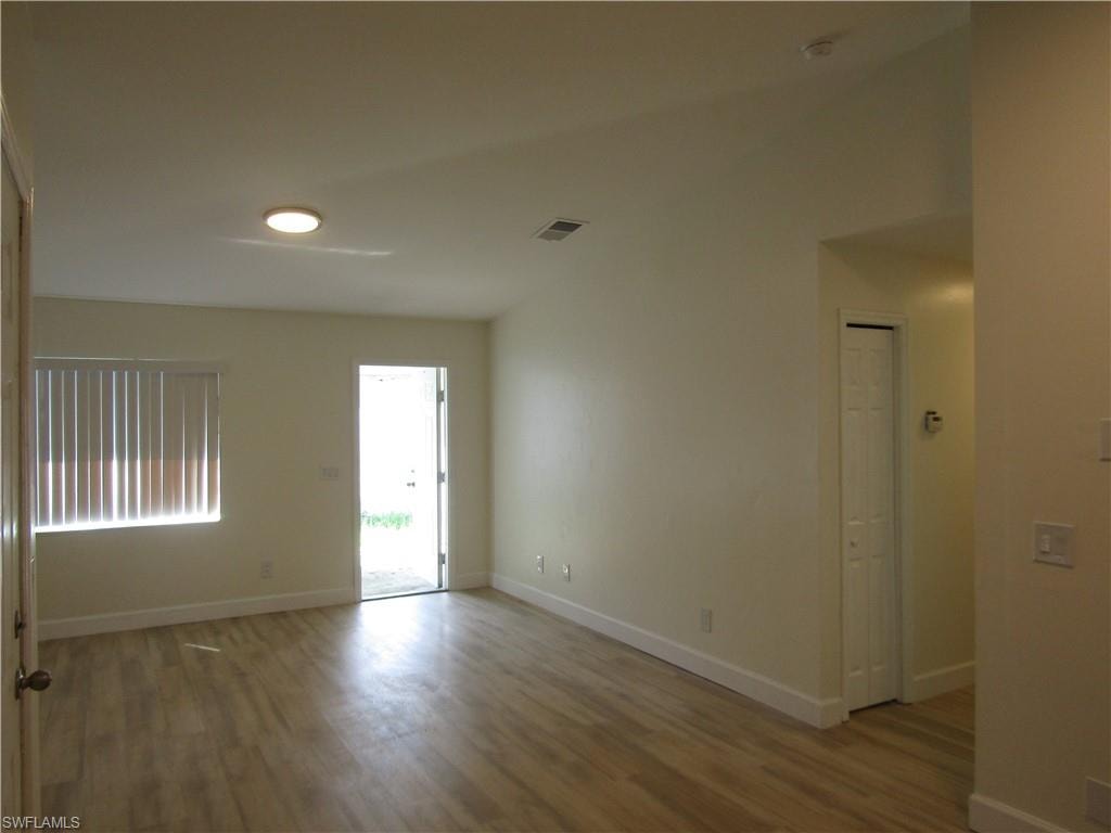 Spacious room featuring wood-finish flooring, light-toned walls, and white trim
