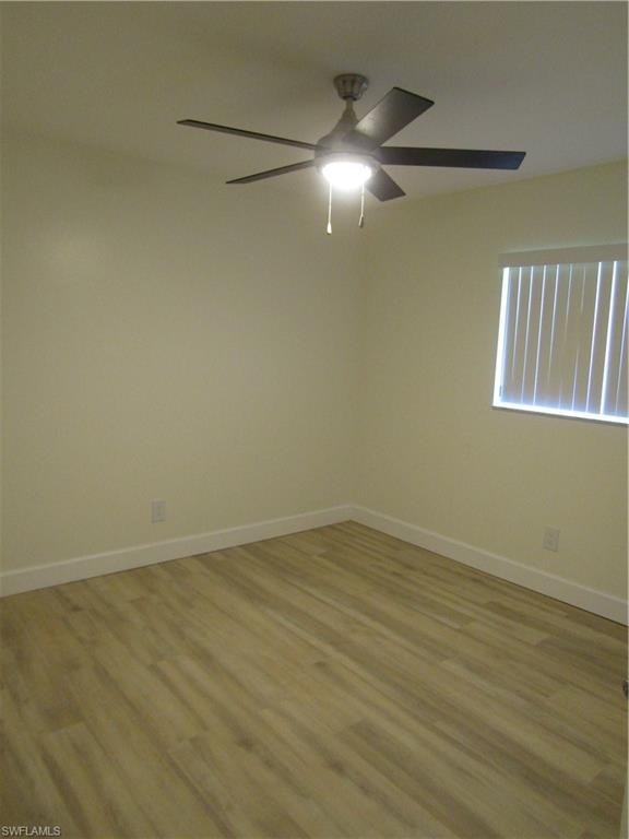 Room featuring light wood-finish flooring, white baseboards, a window with horizontal blinds, and a ceiling fan with integrated lighting