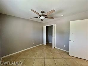 Room featuring light gray walls, tile flooring, a ceiling fan with light fixture, and a bifold door closet