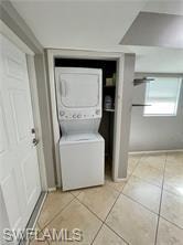 Dedicated laundry closet featuring a stackable washer and dryer, tile flooring, and light gray wall paint