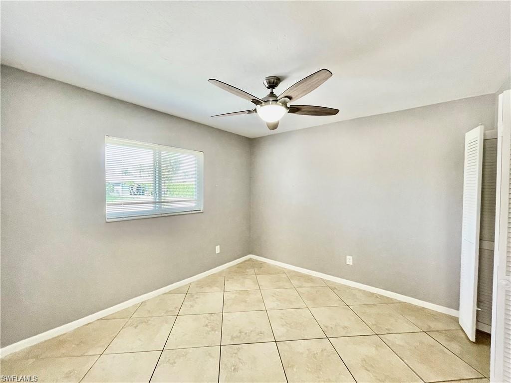 Room featuring large format tile flooring, a window with horizontal blinds, and a ceiling fan with integrated lighting