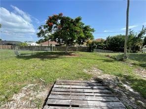 Expansive green space featuring a mature tree with vibrant foliage, perimeter fencing, and partial chain-link fencing