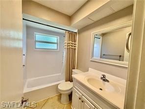 Bathroom featuring a white vanity with integrated sink, a framed mirror, a built-in tub with shower, and tile flooring