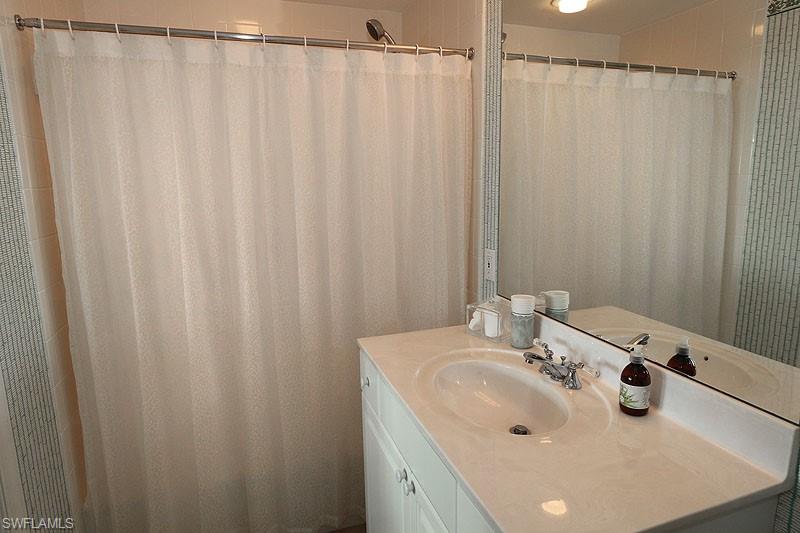 Bathroom featuring a vanity with an integrated sink and chrome fixtures, a full-width wall mirror, and a shower with a privacy curtain