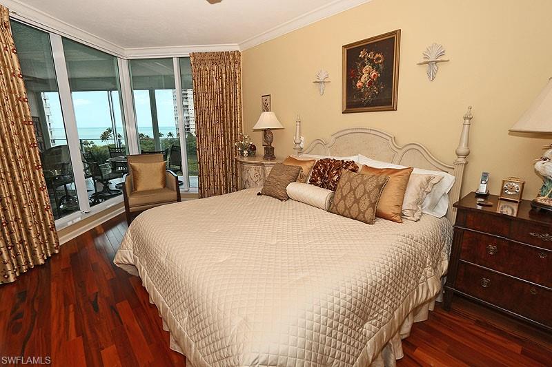 Wood-finish flooring throughout, featuring crown molding, a built-in wall sconce, and floor-to-ceiling windows with a balcony