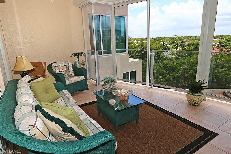 Expansive outdoor living area featuring light-toned tile flooring and a glass railing system