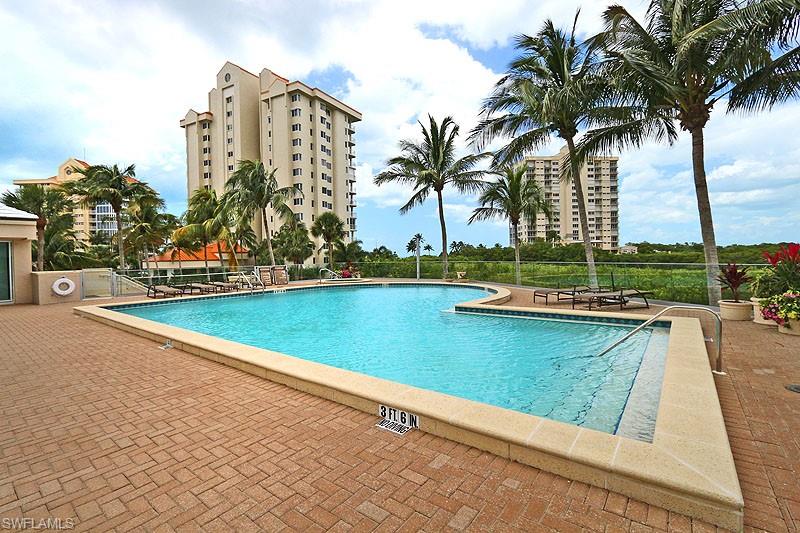 Expansive outdoor swimming pool with integrated spa, surrounded by a brick paver deck and tropical landscaping