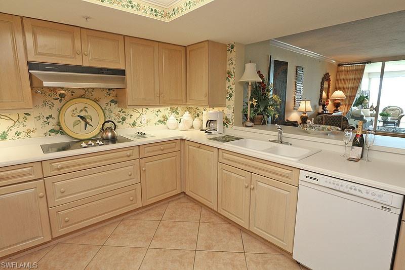 Kitchen featuring light wood cabinetry, a built-in cooktop, and a double basin sink