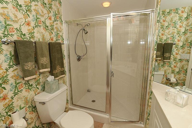 Shower enclosure with sliding glass doors, chrome fixtures, and tiled interior