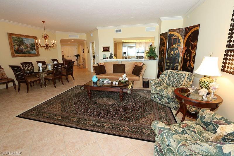 Spacious interior featuring tile flooring, a dining area with a chandelier, crown molding, and a kitchen pass-through