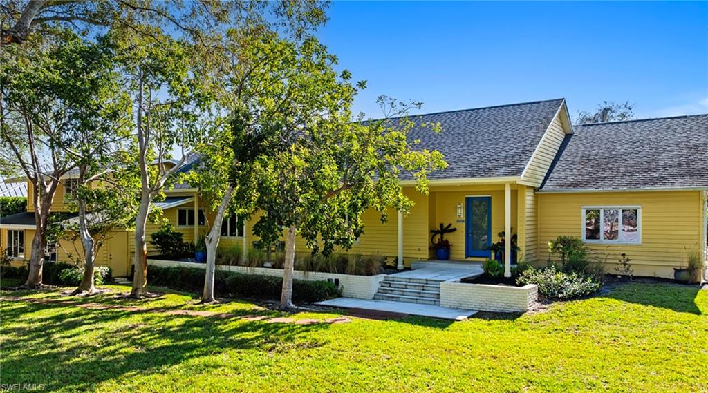Rear view of house featuring roof with shingles and a yard