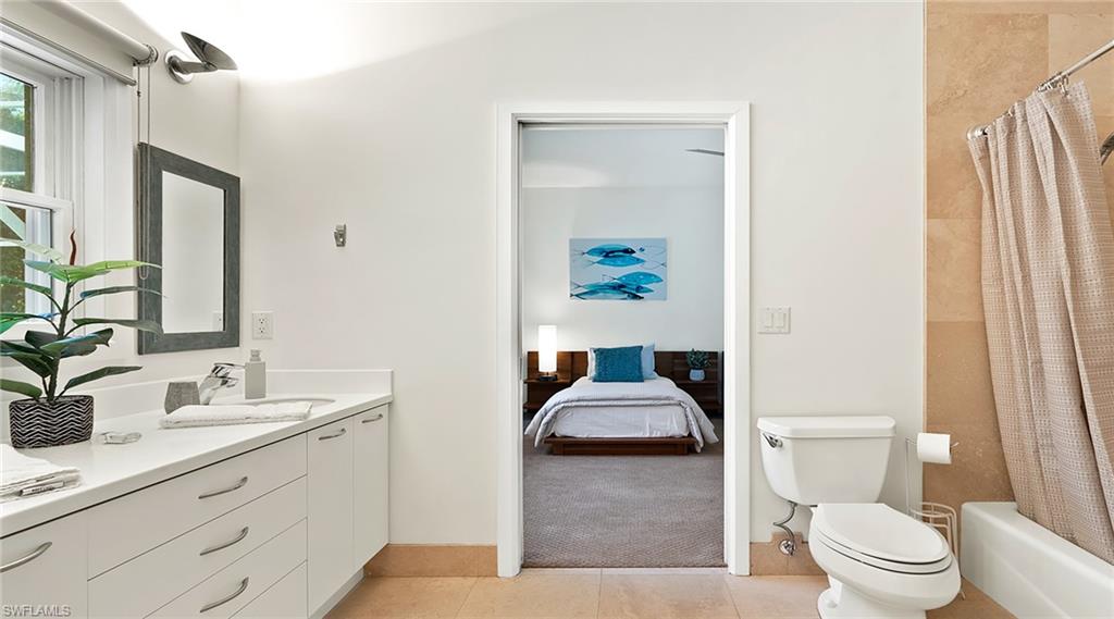 Full bathroom featuring shower / bath combo, double vanity, light colored carpet, ensuite bath, and light tile patterned floors
