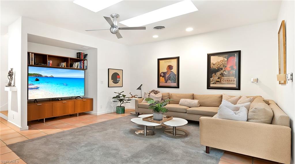 Living area with a skylight, light tile patterned floors, ceiling fan, and recessed lighting