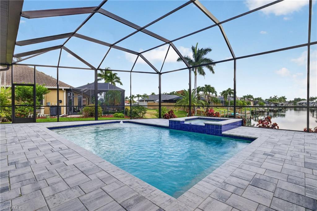 Screened lanai featuring a swimming pool, integrated spa, and paver decking
