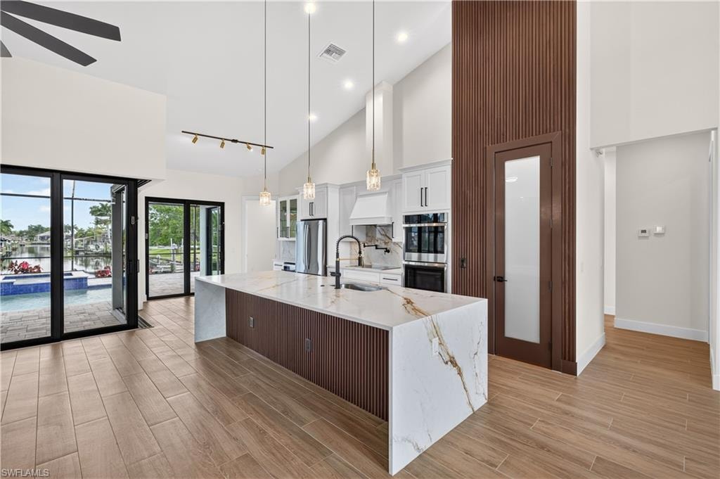 Open-concept kitchen featuring a waterfall island with a quartz countertop and integrated sink