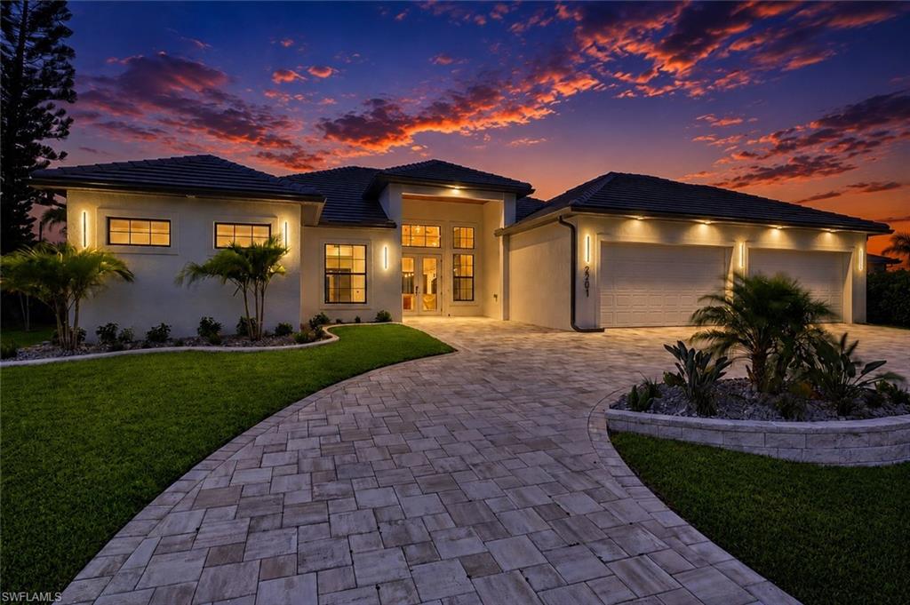 Contemporary single-story residence featuring a paved driveway, a two-car garage with individual doors, and a manicured lawn