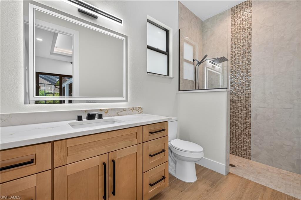 Contemporary bathroom featuring a wood-finish vanity with a quartz countertop, an integrated sink, and matte black fixtures