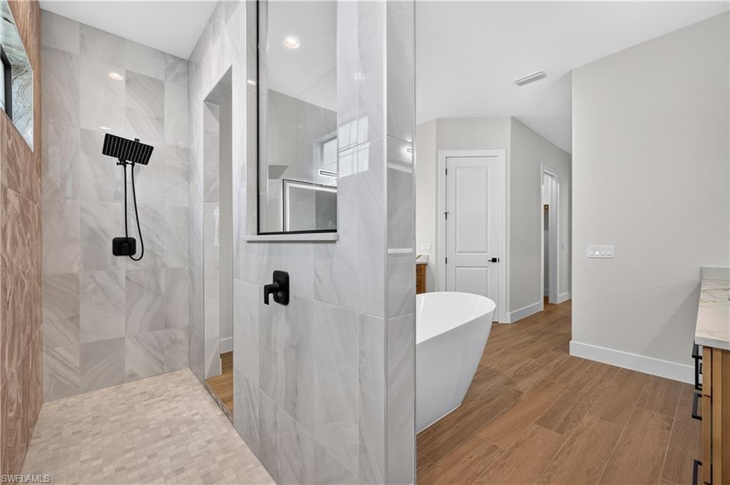 Walk-in shower with large format tile walls, black fixture finishes, and a mosaic tile floor
