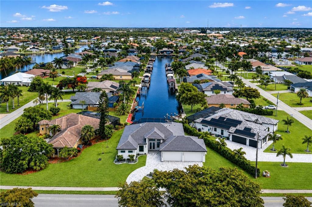 Waterfront property featuring a paver driveway, two-car garage, and mature palm trees