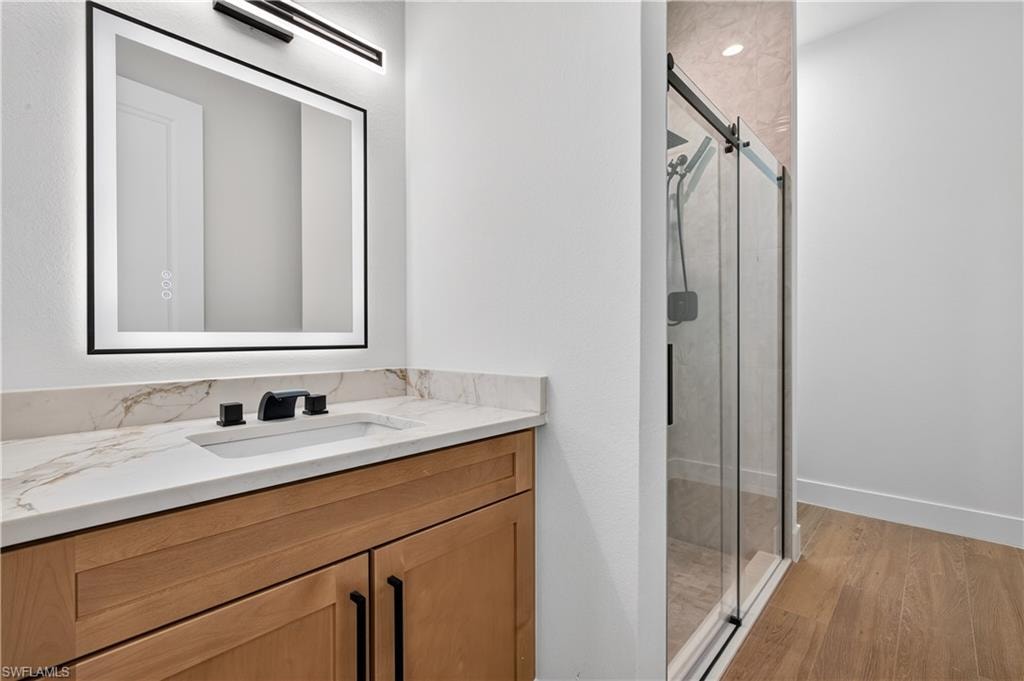 Bathroom vanity featuring a rectangular undermount sink, a stone-finish countertop, and matte black fixtures