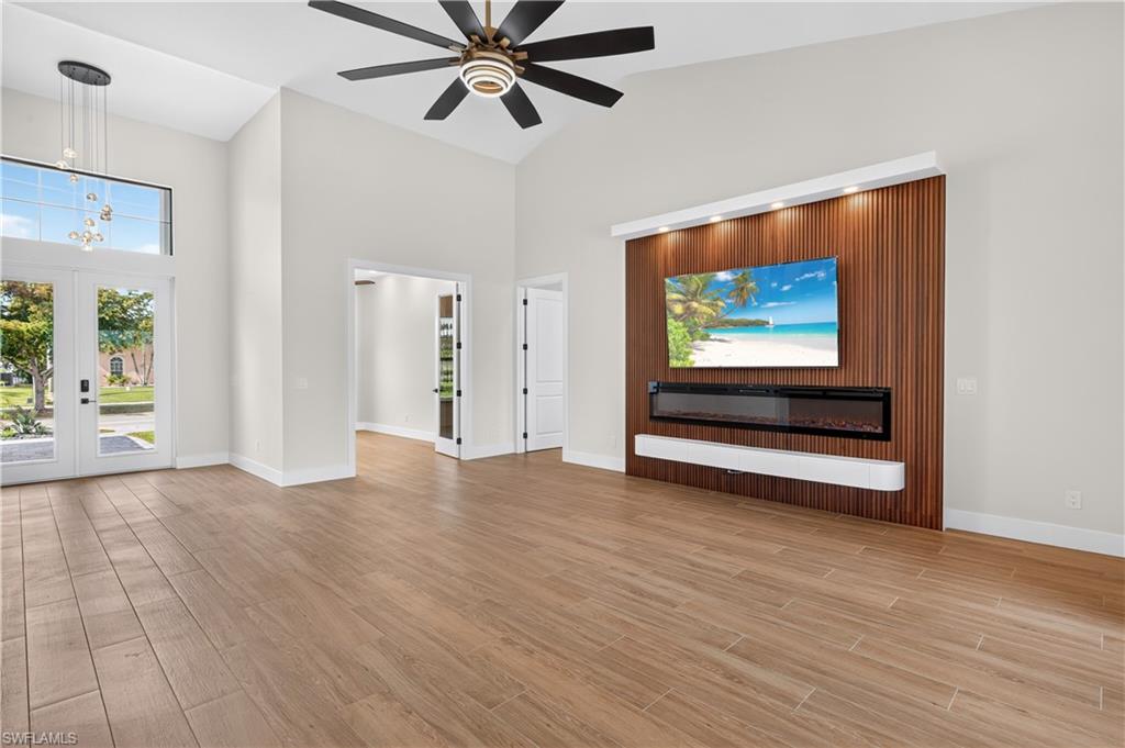Vaulted ceilings with a ceiling fan, a contemporary chandelier, and wood-finish flooring
