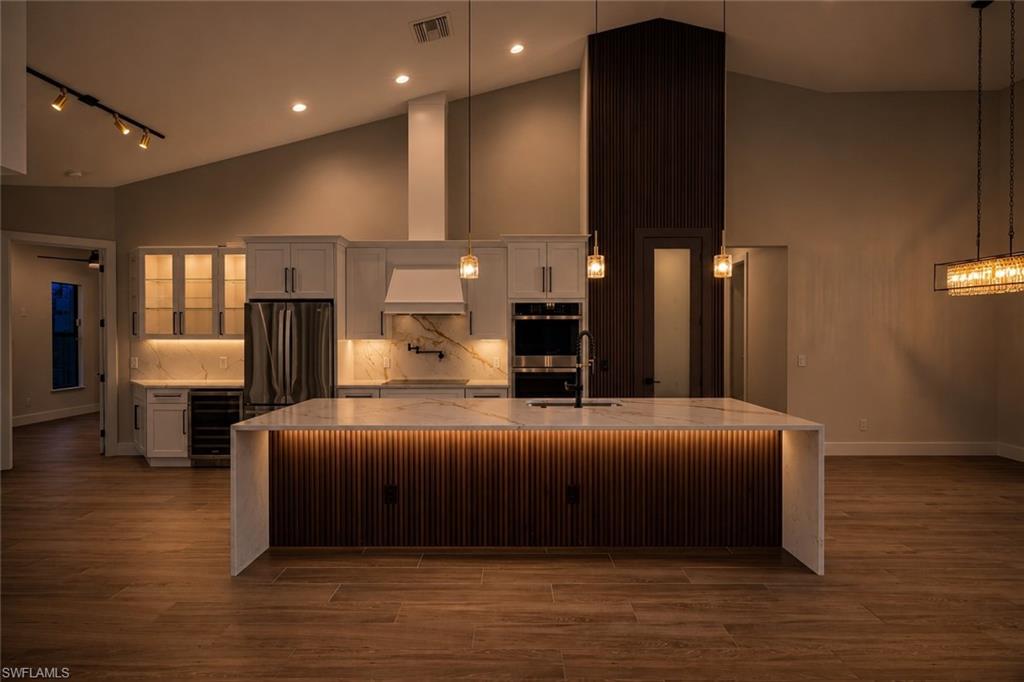 Kitchen featuring a large waterfall island with integrated lighting and a fluted wood-finish panel base