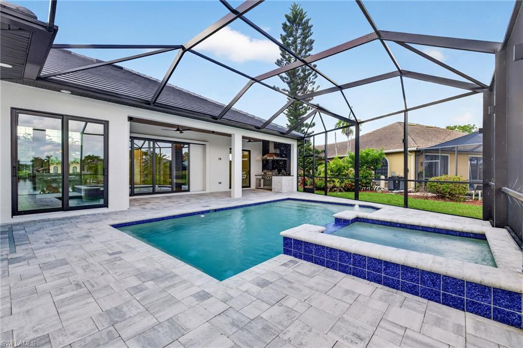 Screened lanai featuring a swimming pool and elevated spa with blue tile accents