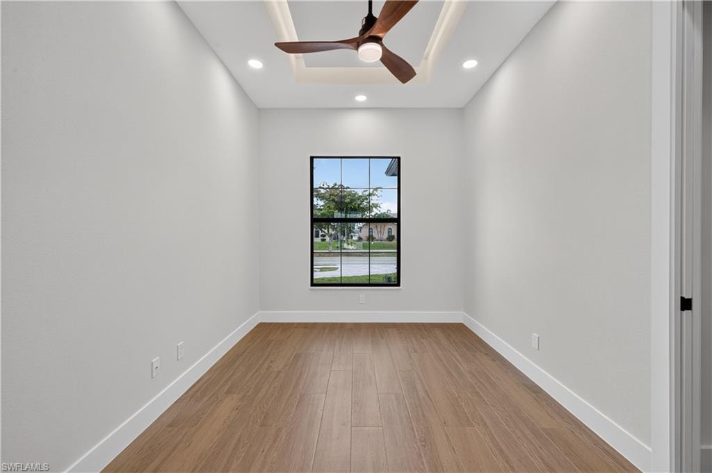 Interior room featuring wood-finish flooring, white painted walls, and a black-framed window